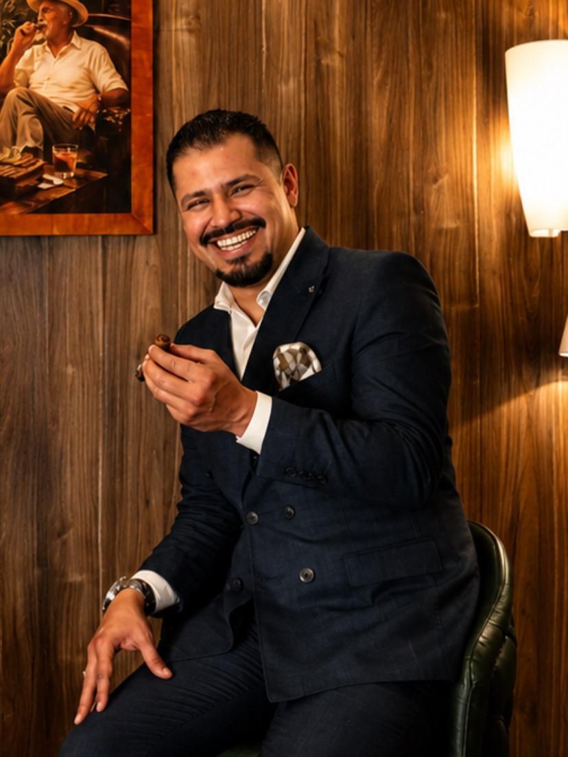Alejandro sonriendo con un habano en la mano, en un salón con paredes de madera