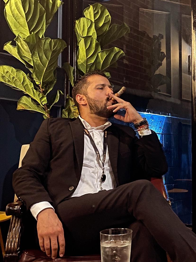 Alejandro fumando un habano en un sillón de cuero